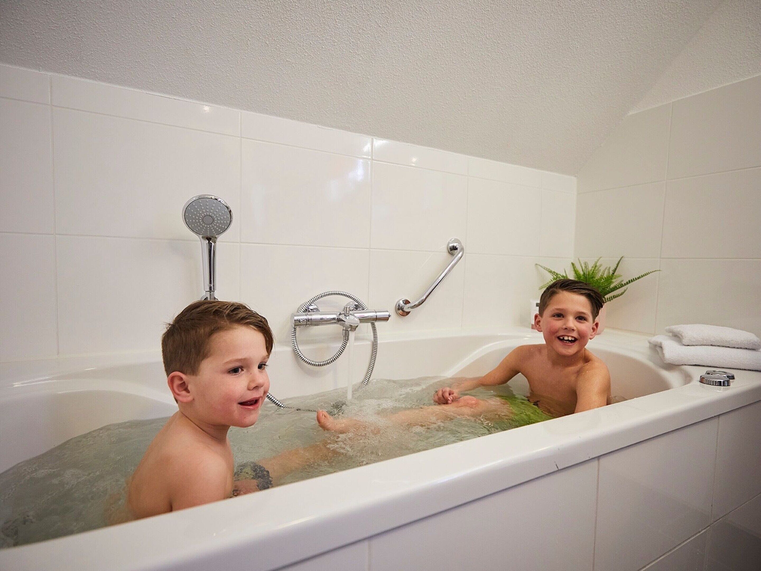 Ein Badezimmer mit einer Badewanne, einer Duschbrause und einer Handstange.