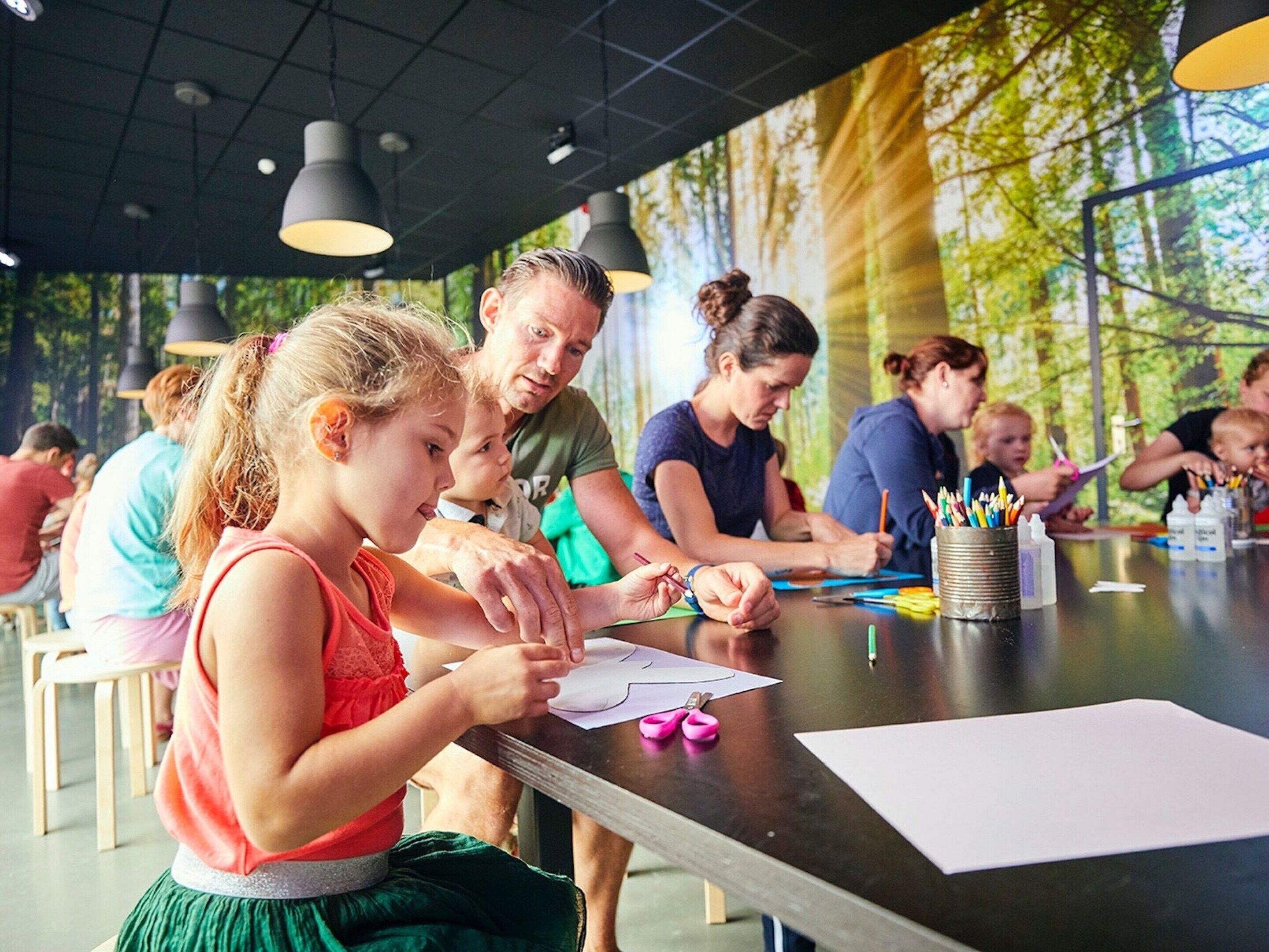 A group of people engaged in a craft activity at a table with art supplies.