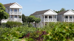 A row of white houses with balconies, surrounded by lush greenery. - Restyled Villa With Dishwasher, Near the Beach (Kamperland)