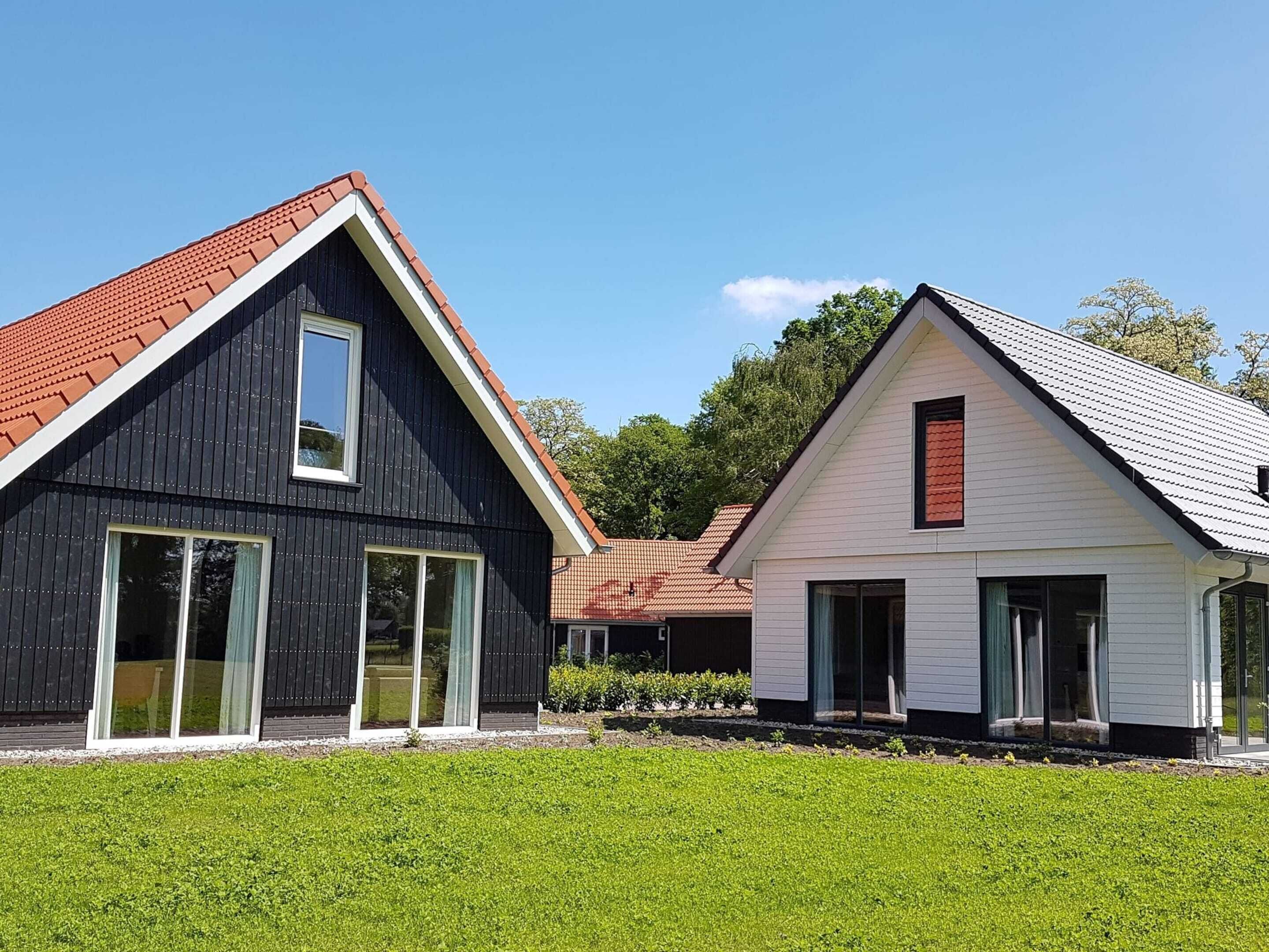 Two modern houses with distinct architectural styles, featuring large windows and different roof colors.
