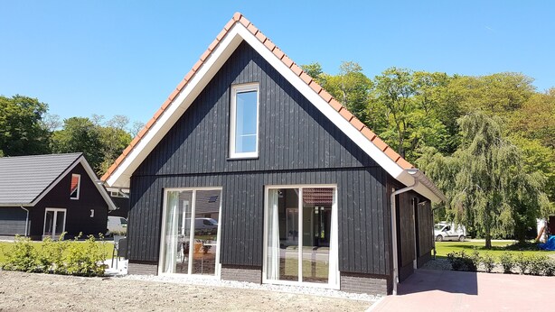 A modern building with a dark facade, large windows, and a sloped roof. - Modern Villa With Garden (Almen)