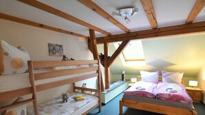 Una camera da letto mansardata accogliente con un letto a castello, un letto singolo e un lucernario.