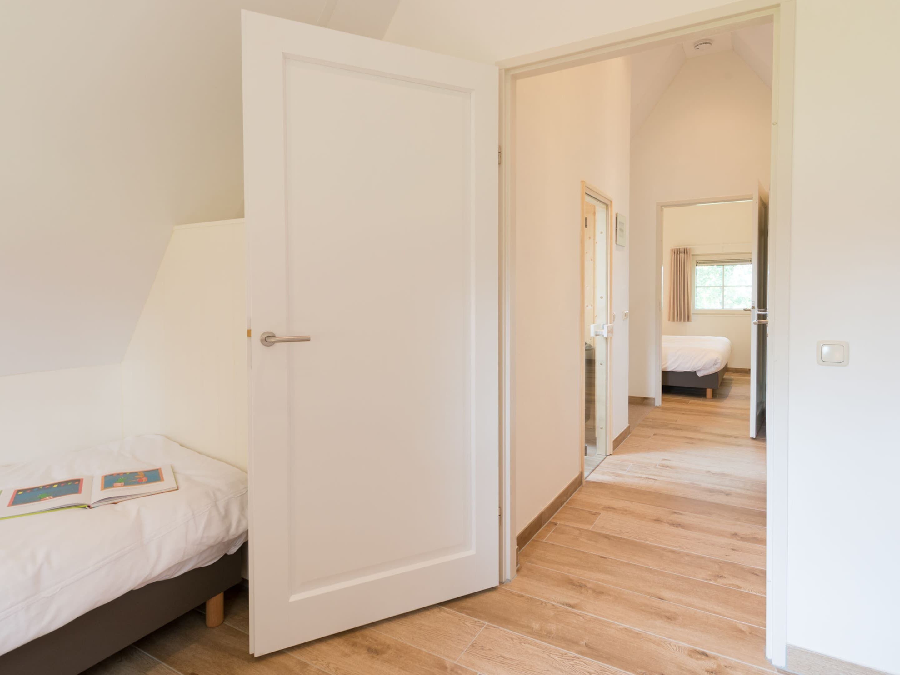 Un dormitorio con una cama, una puerta y un pasillo que da a otra habitación.