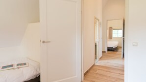 Quarto com cama, porta e corredor que dá para outro cômodo.