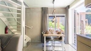 A modern interior with a dining area, a staircase, and a view of greenery. - Lodge in Vlissingen Near North Sea Beach (Vlissingen)
