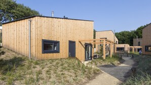 A wooden building with a window and door, a pathway leading to it, and a grassy area. - Lodge in Vlissingen Near North Sea Beach (Vlissingen)