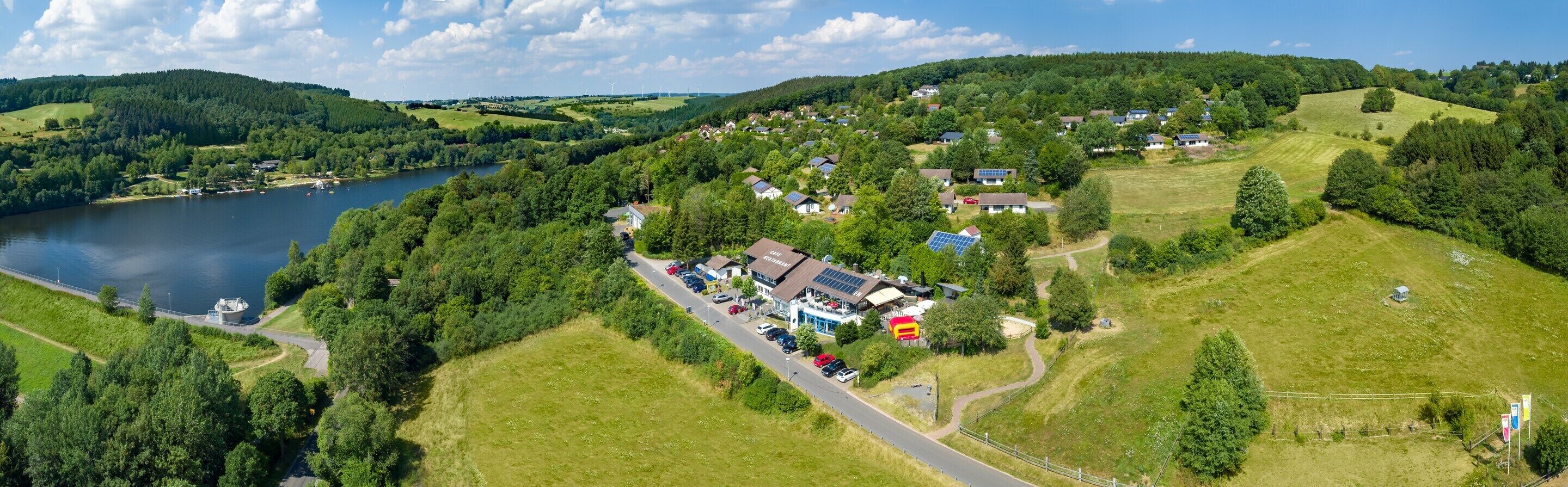 Vista aérea de un pequeño pueblo con casas, una carretera y un lago.
