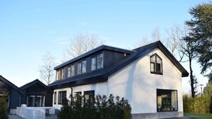 A modern two-story house with a sloped roof, large windows, and a well-maintained lawn. - Villa in Netherlands With Private Pool (Voorthuizen)