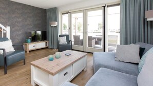 A modern living room with a sofa, a coffee table, a TV, and a sliding glass door leading to an outdoor area.