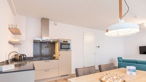 Een moderne keuken met een ingebouwde oven, een koffieapparaat en een servies op het aanrecht.