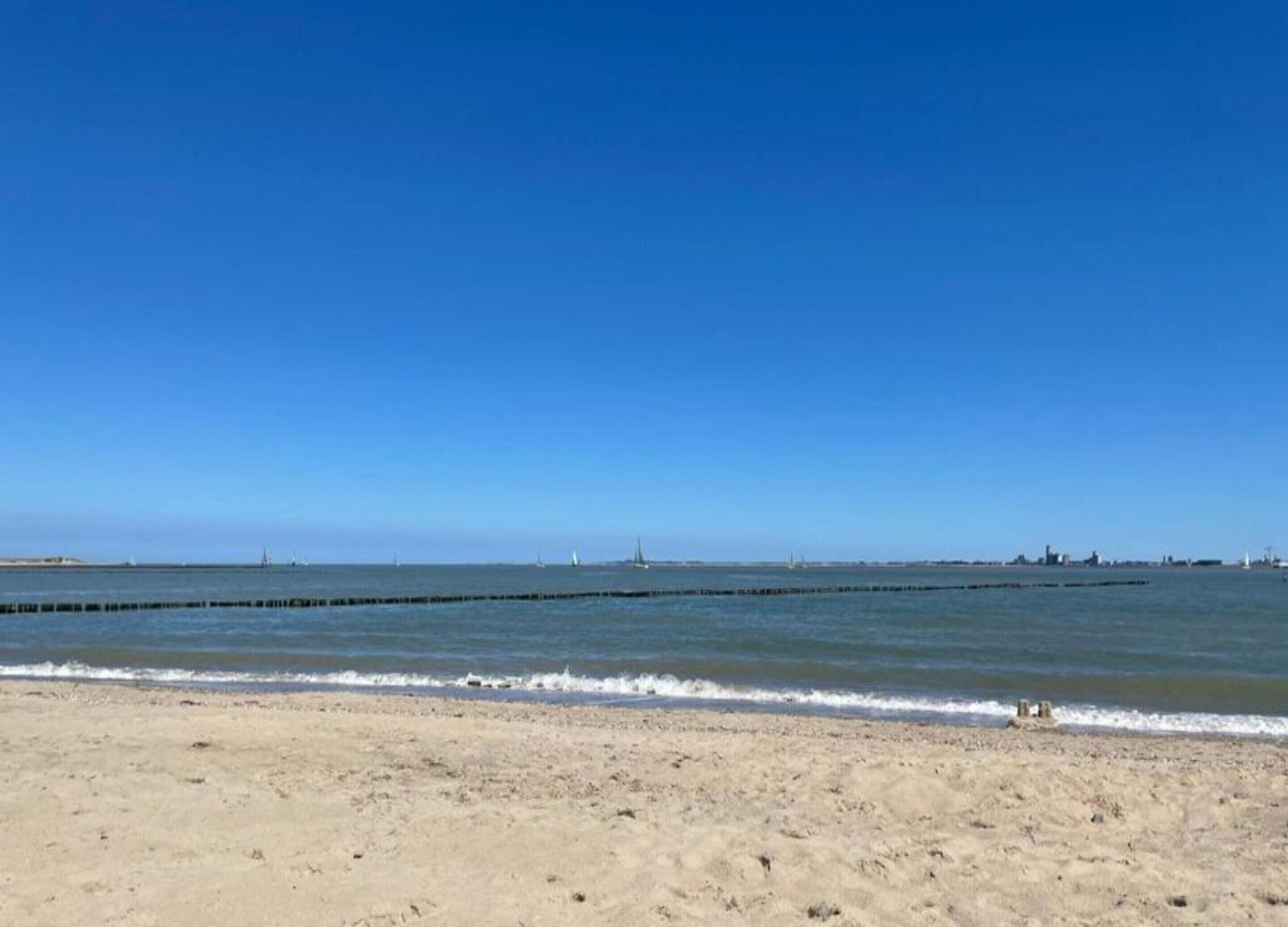 A sandy beach with calm waters and a clear blue sky.