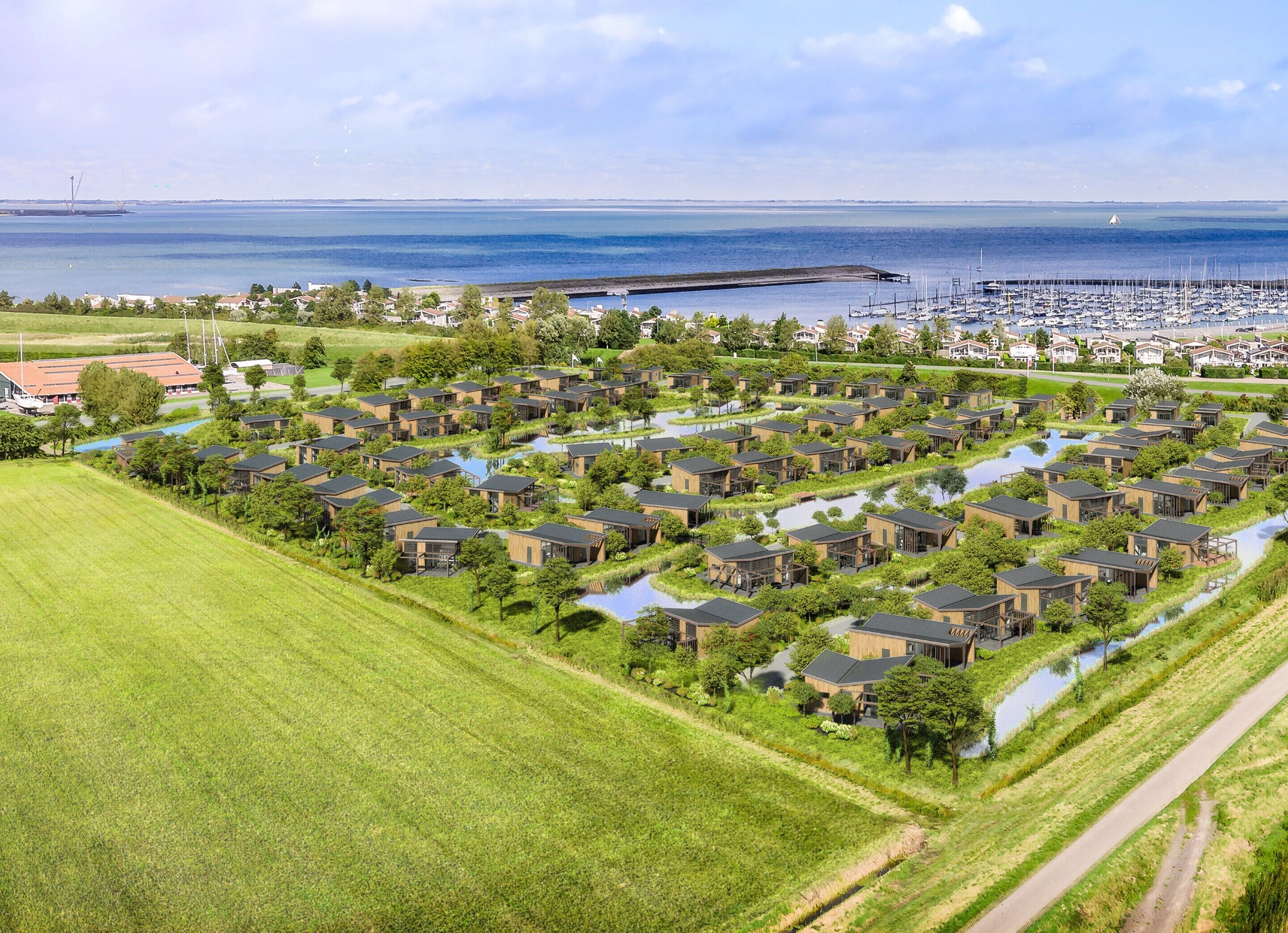 A residential area with modern houses arranged in a grid pattern, a marina with boats, and a large body of water in the background.