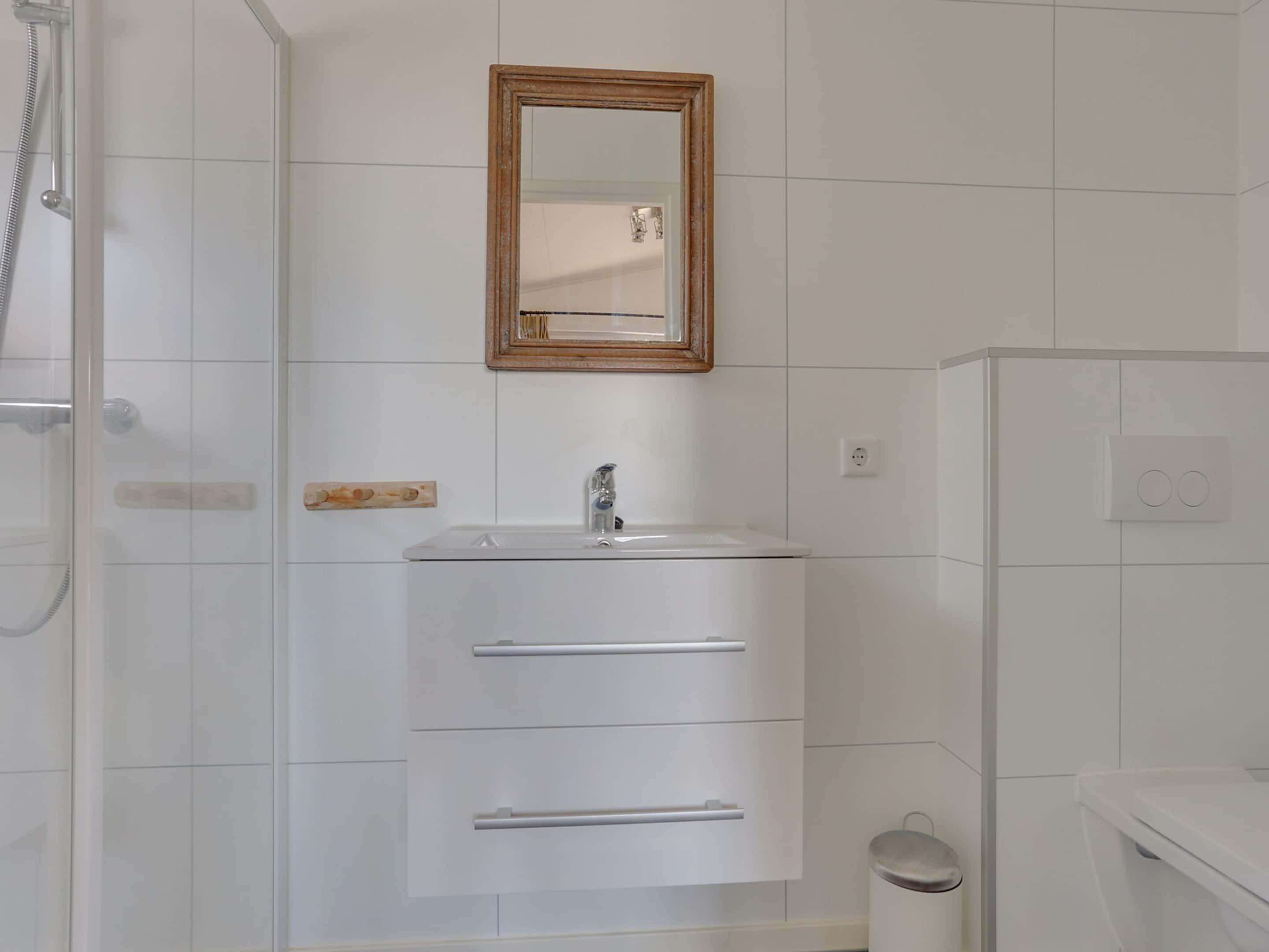 A bathroom with a white sink, a mirror, and a shower.