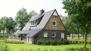 A house with a sloped roof, wooden siding, and a well-maintained lawn. - Stylish Retreat in Hellendoorn (Hellendoorn)