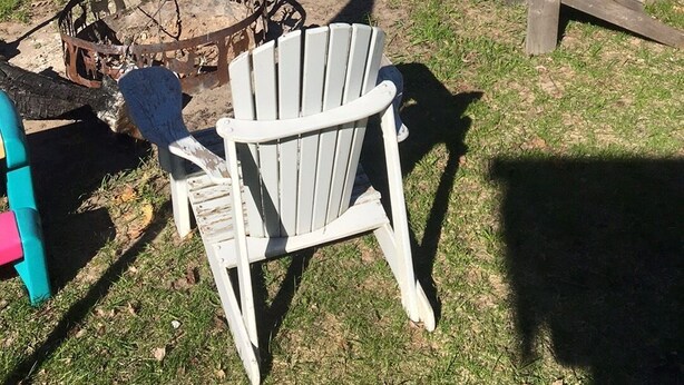 Kaunis paikka järven rannalla, jossa on Adirondack-tyylisiä puutarhatuoleja, nuotiopaikka ja laituri, joka ulottuu veteen.