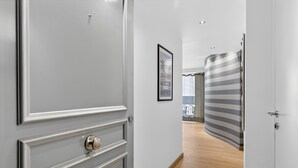 Un pasillo con una puerta, un cuadro en la pared y una cortina a rayas.
