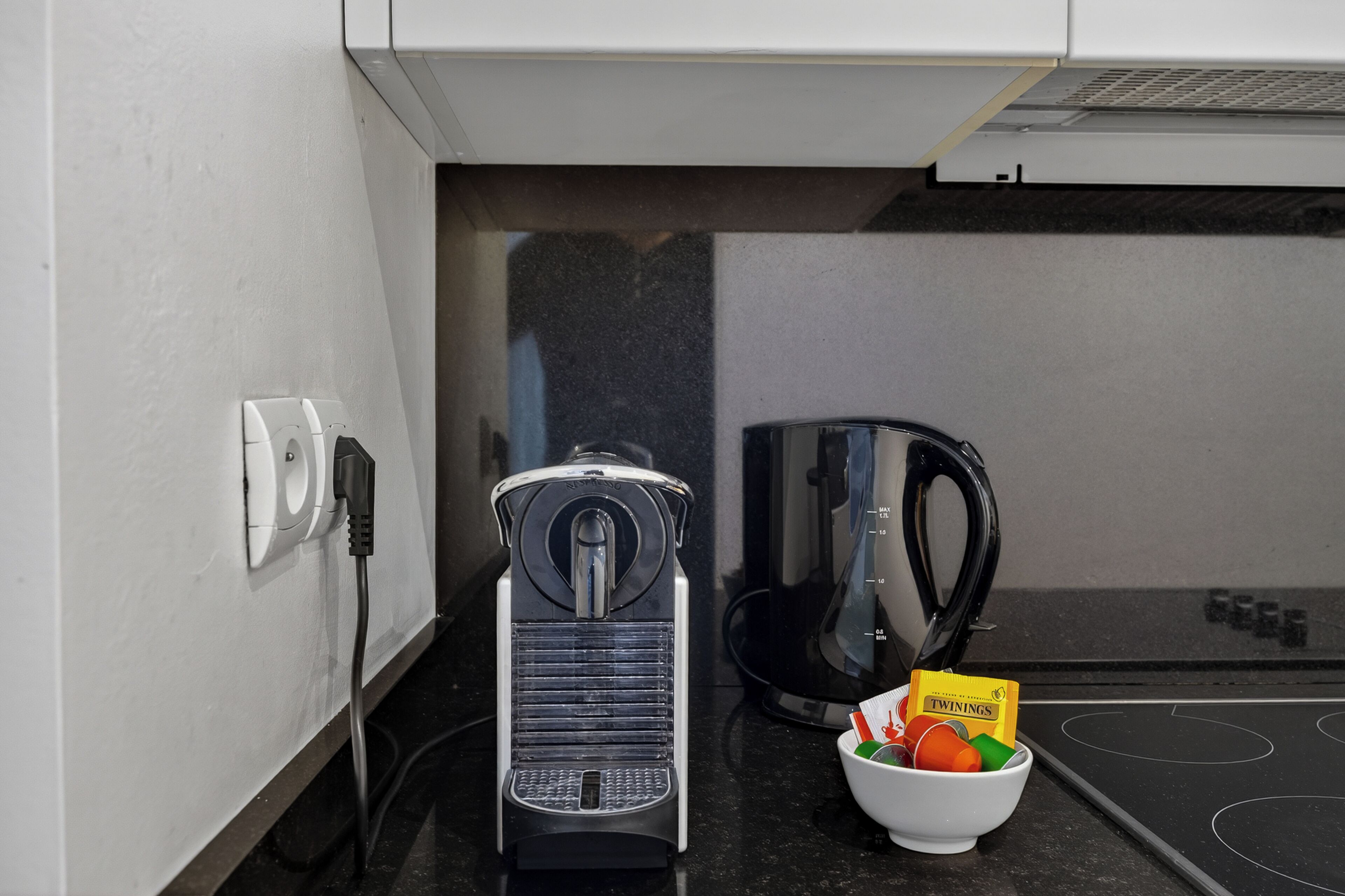 Une cuisine équipée d’une machine à café, d’une bouilloire et d’un récipient contenant des aliments.
