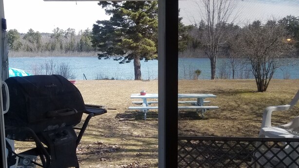 Un patio cubierto con una parrilla, mesa de picnic y sillas.