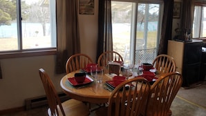 Comedor con una mesa redonda de madera, seis sillas de madera y vajilla roja.
