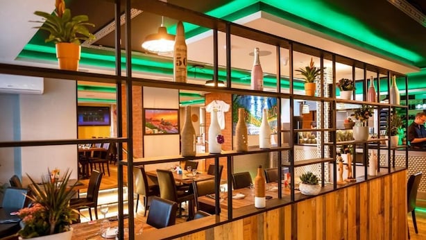 Ein Restaurant mit Holzwänden, Tischen, Stühlen und Topfpflanzen.