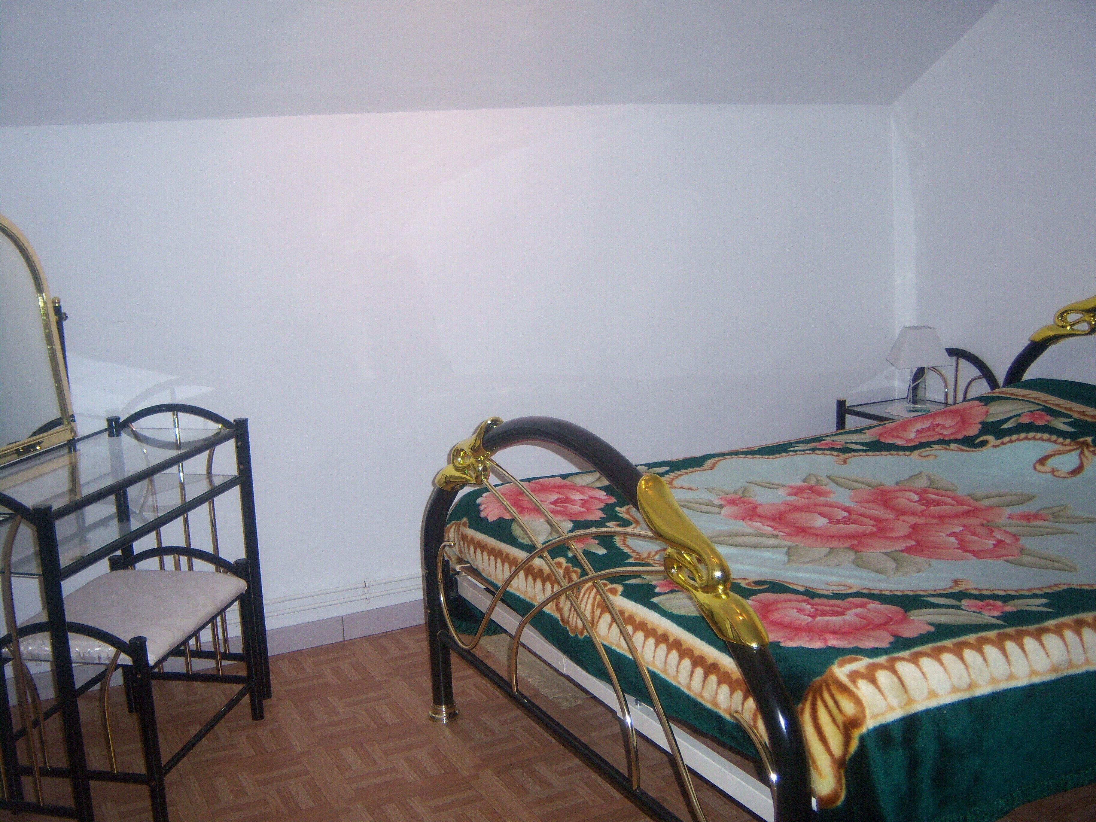A bedroom with a bed, a chair, a table, and a lamp.