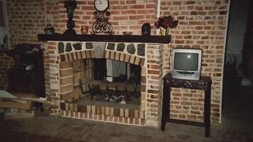 Ein Kamin aus Ziegelsteinen mit einem Fernseher auf einem kleinen Tisch daneben.