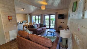 A cozy cabin interior with a sofa, a dining table, a TV, and a fireplace.
