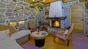 A cozy room with stone walls, a fireplace, wooden furniture, and a teddy bear on a sofa. - Sobol in Kočičin (Haus für 6-9 Personen) (Kuzelj)