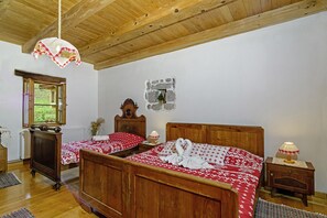 Une chambre à coucher en bois avec deux lits, un mur en pierre, un plafond en bois et une fenêtre.