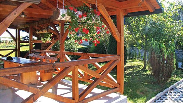 Un porche de madera con un banco y cestas de flores colgantes.