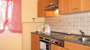 Una cocina con armarios de madera, salpicadero de azulejos, estufa y lavamanos.