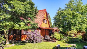 A wooden house with a red roof, surrounded by lush greenery and a well-maintained lawn. - 3 bedroom lovely home in Nowe Warpno (Nowe Warpno)