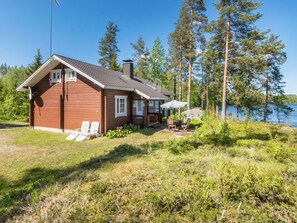 A wooden cabin with a deck, surrounded by trees and a lake. - Pajulintu by Interhome (Parikkala)