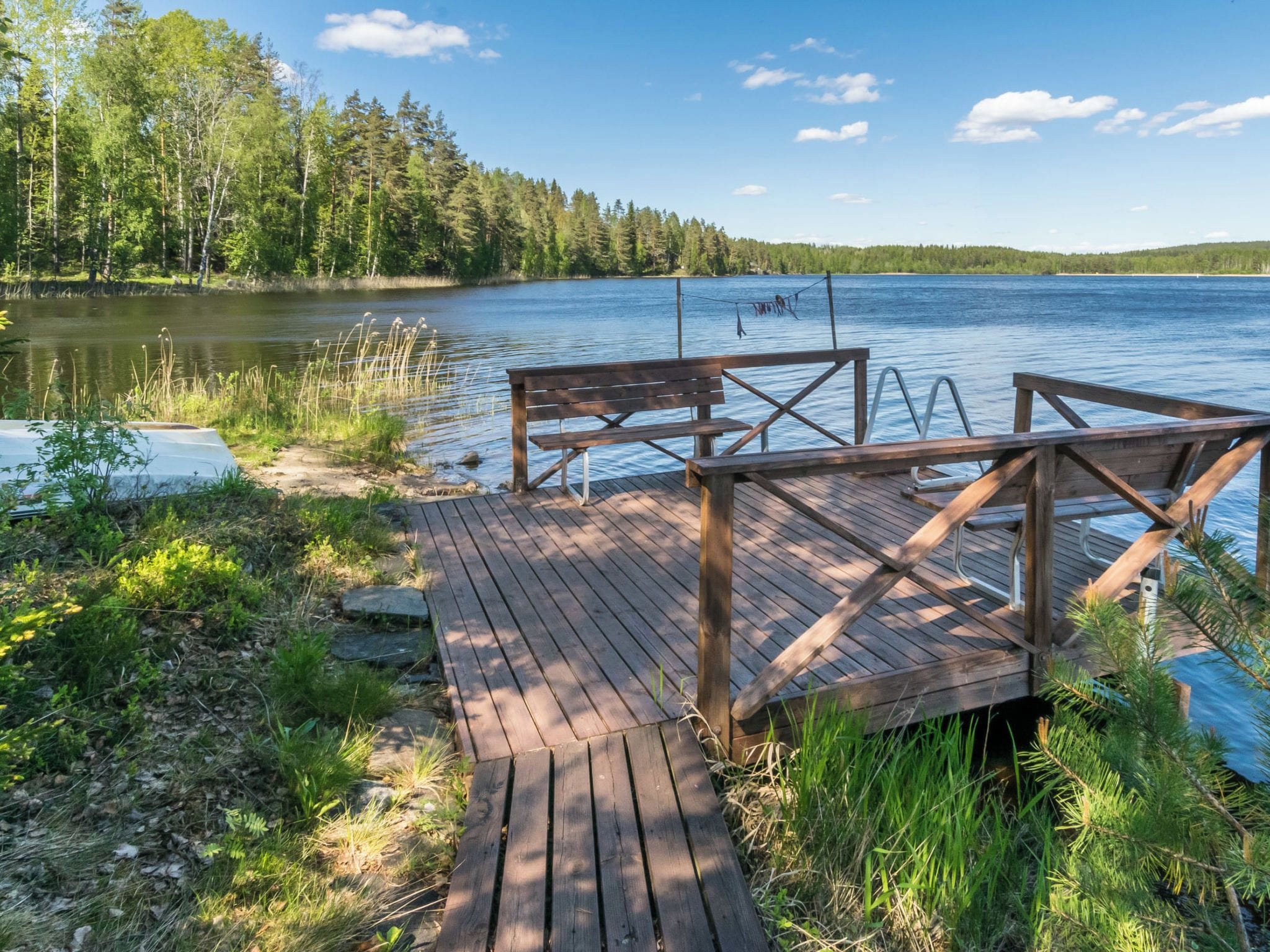A wooden dock extending into a calm lake, surrounded by dense forest.