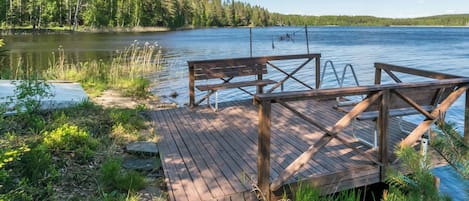 A wooden dock extending into a calm lake, surrounded by dense forest.