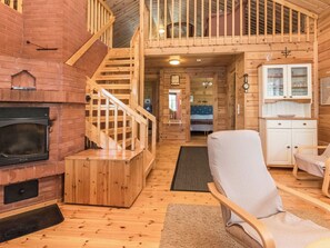 A wooden interior with a fireplace, a staircase, a living area with a sofa, and a kitchen with cabinets. - Pajulintu by Interhome (Parikkala)