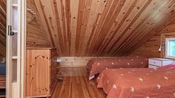 Une cabane en bois avec une chambre à coucher en mezzanine, deux lits, une commode et une fenêtre.
