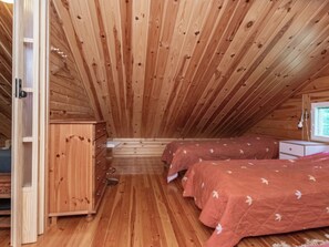 A wooden cabin with a loft bedroom, two beds, a dresser, and a window. - Lehtimaja by Interhome (Parikkala)