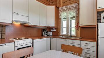 Une cuisine de taille réduite, avec des meubles blancs, une cuisinière, un lave-vaisselle et un évier.