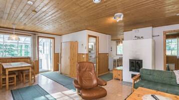 A wooden interior with a dining area, a leather chair, a sofa, and a fireplace.