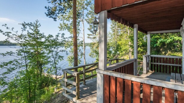 A wooden deck with a railing overlooking a lake, surrounded by trees. - Kiviaho by Interhome (Parikkala)