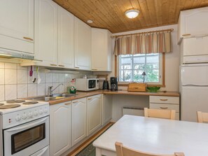A compact kitchen with white cabinets, a stove, a microwave, and a refrigerator. - Kiviaho by Interhome (Parikkala)