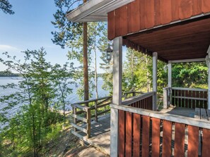 A wooden deck with a railing overlooking a body of water, surrounded by trees. - Kiviaho by Interhome (Parikkala)
