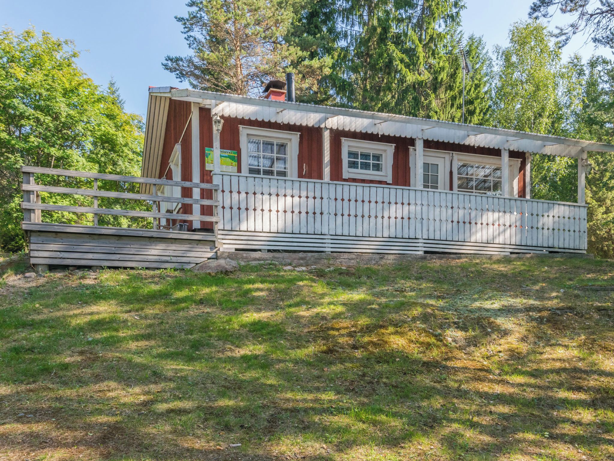 Eine Holzhütte mit Veranda, umgeben von Bäumen.
