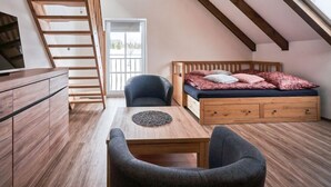 A loft bedroom with a wooden bed, a desk, and a chair. There is a window and a door. - Na Pomezkách by Interhome (Malá Úpa)
