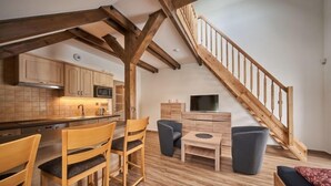 A modern kitchen with wooden beams, a dining area with wooden chairs, a small table, and a staircase. - Na Pomezkách by Interhome (Malá Úpa)