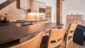 A modern kitchen with wooden beams, a central island, and a dining area with chairs. - Na Pomezkách by Interhome (Malá Úpa)