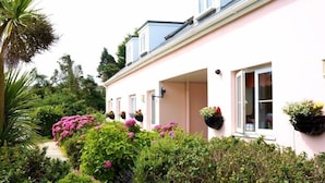 A pink house with hanging flower baskets and a garden path.