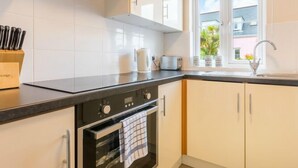 Een moderne keuken met witte kasten, een zwart aanrecht, een oven en een raam met uitzicht op groen.