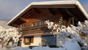 Un chalet en bois doté d’un toit à pente, de grandes fenêtres et d’un balcon.